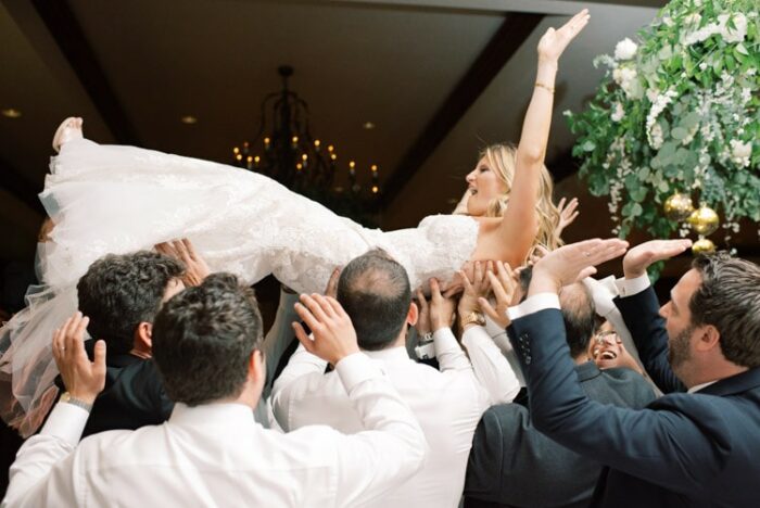 Bride being hoisted up by group of people