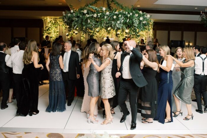 Dancing in the grand ball room with large greenery decoration hanging above