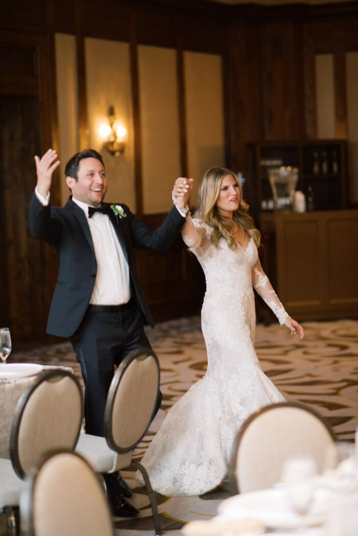 Married couple walking into room together holding hands