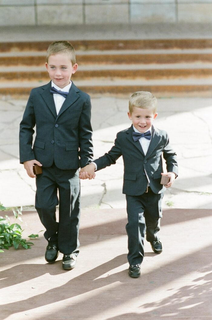Ring bearer kids in black suits walking
