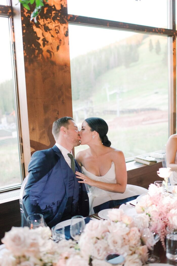 Bride and groom kissing at wedding reception table