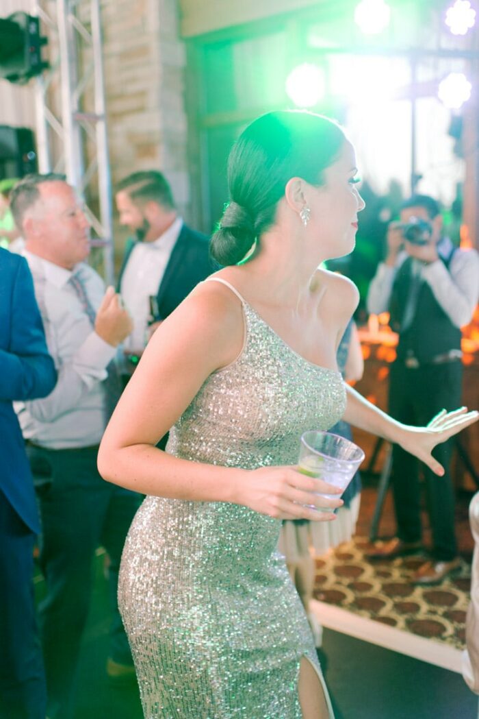Just married woman dancing in silver sparkling dress with drink
