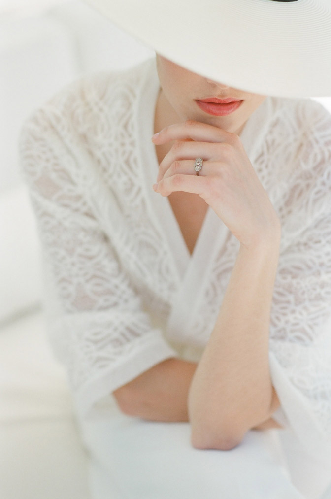 Woman with engagement ring wearing white lace jacket