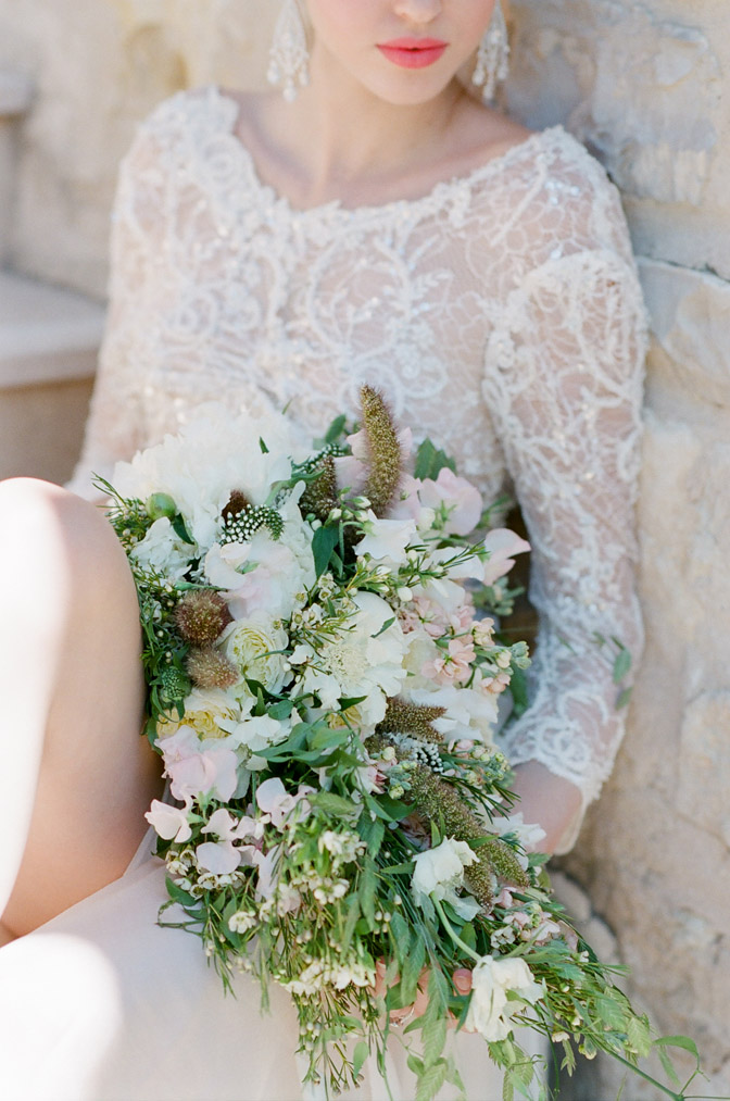 View of bride in white lace wedding dress holding white bouquet