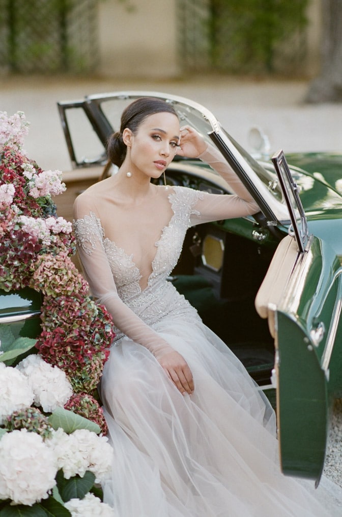 Bride posing in a classic convertible at her destination wedding in France