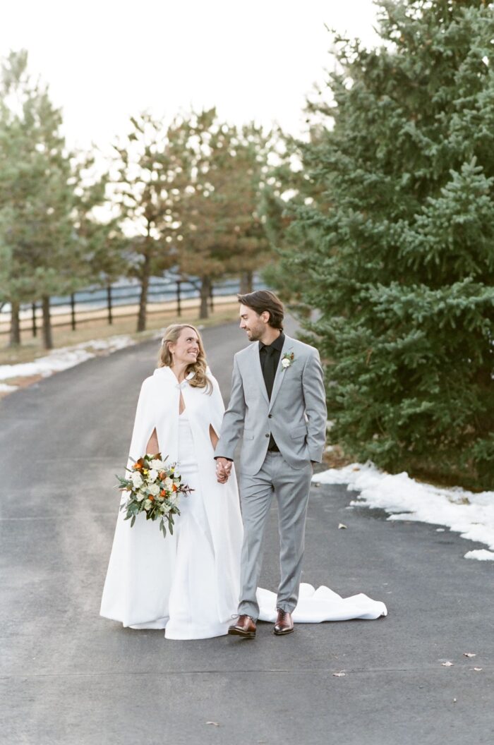 Bride and groom holding hands walking down the street together
