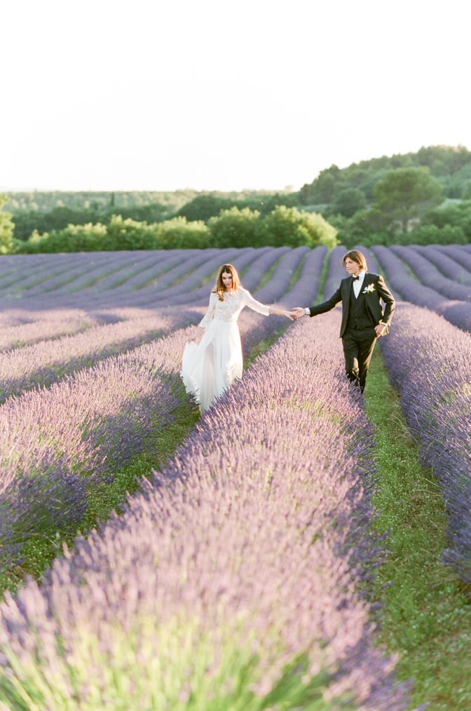 Bride and Groom walking hand in hand through a blooming lavender field in the Luberon in Provence