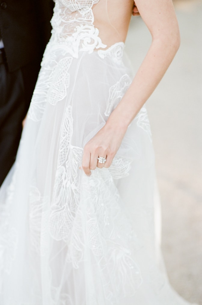 Closeup of a bride holding her wedding dress while wearing her luxury designer engagement ring by Susie Saltzman