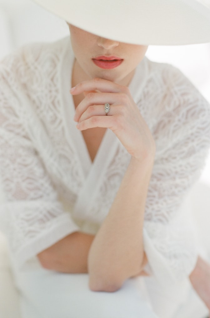 Closeup of bride wearing a hat and showing her unique luxury designer engagement ring by Michaela Roemer