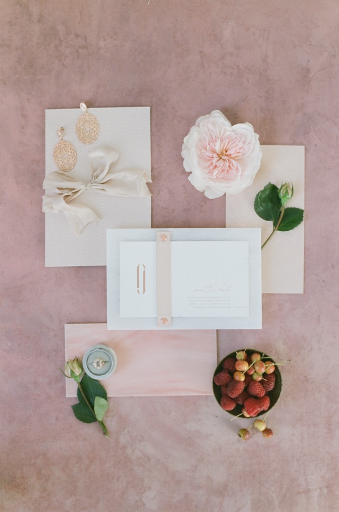 Flatlay of luxury acrylic wedding invitation on red backdrop