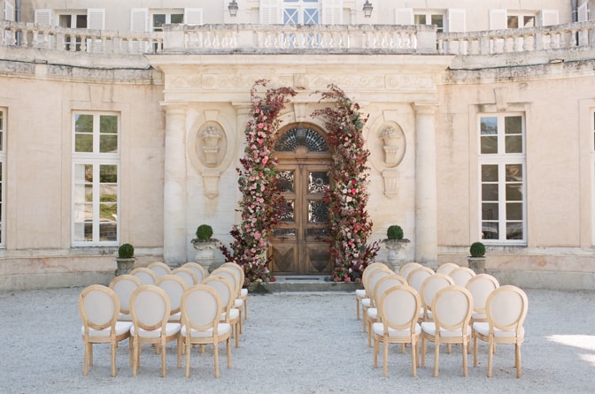 Flower wedding arch in red, blush and pinks adorning the entrance of Chateau Martinay in Provence