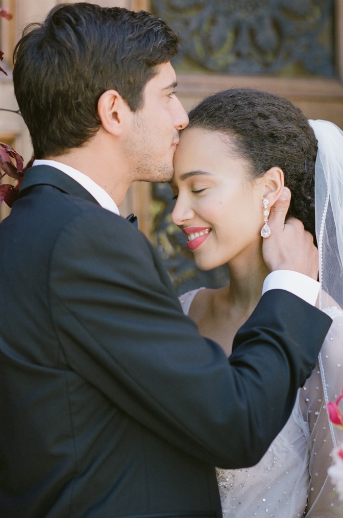 Groom kissing his bride on her forehead in front of Chateau Martinay in Provence