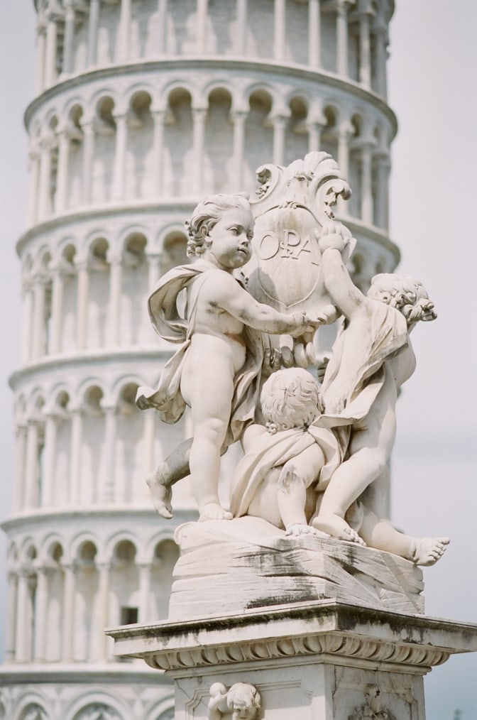 Closeup of baby statues in front of the Leaning Tower in Pisa Italy