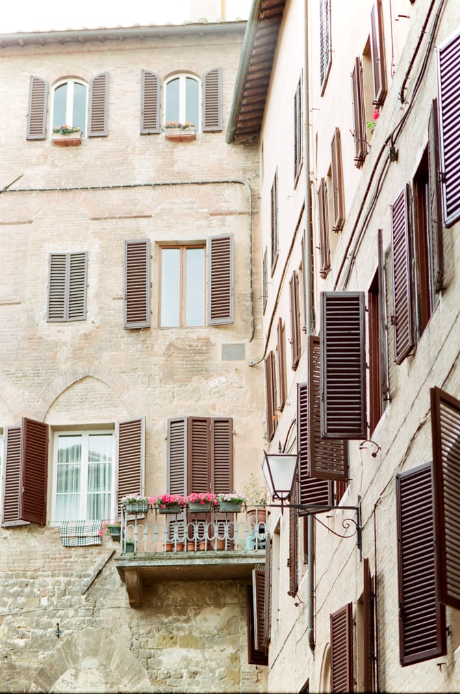 Beige-colored building in Siena with its brown window shutters in Siena Italy