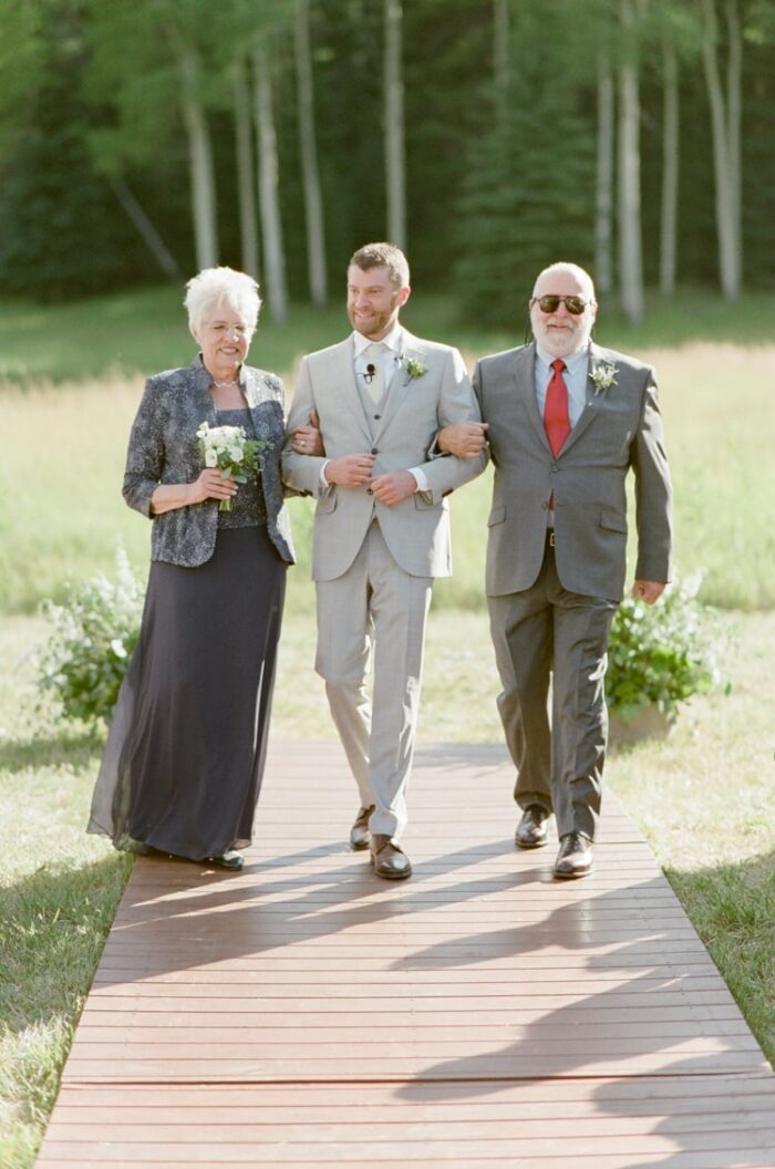 Groom and his parents walking down the aisle at Colorado wedding