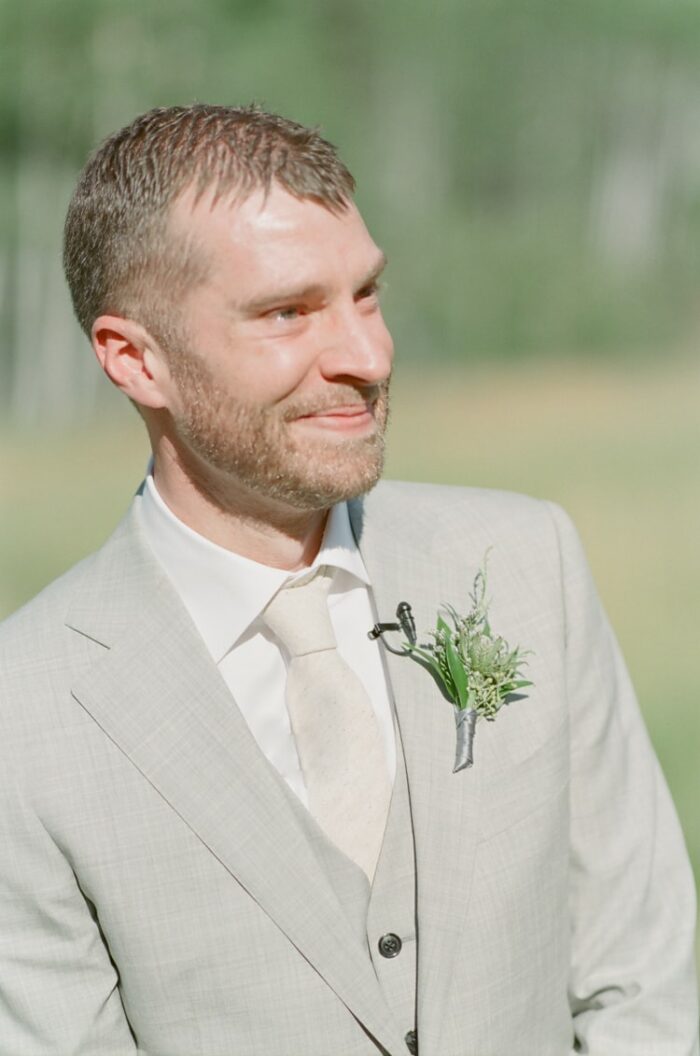 Groom smiling and crying when seeing his bride for the first time on wedding aisle