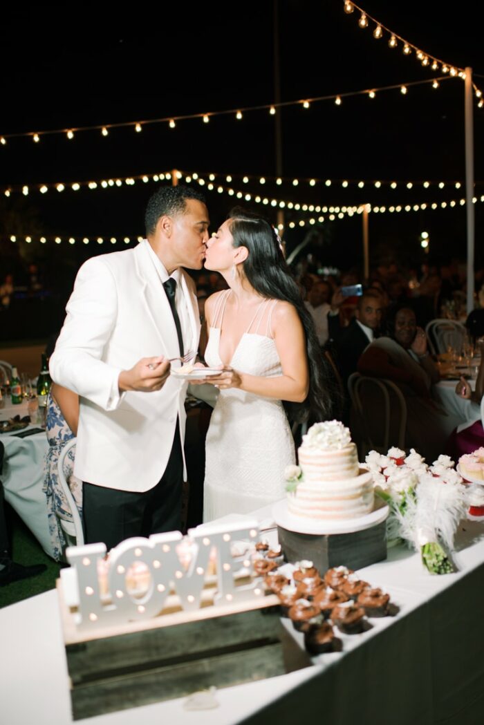 Bride and groom kissing each other after cutting their cake during their wedding reception in California