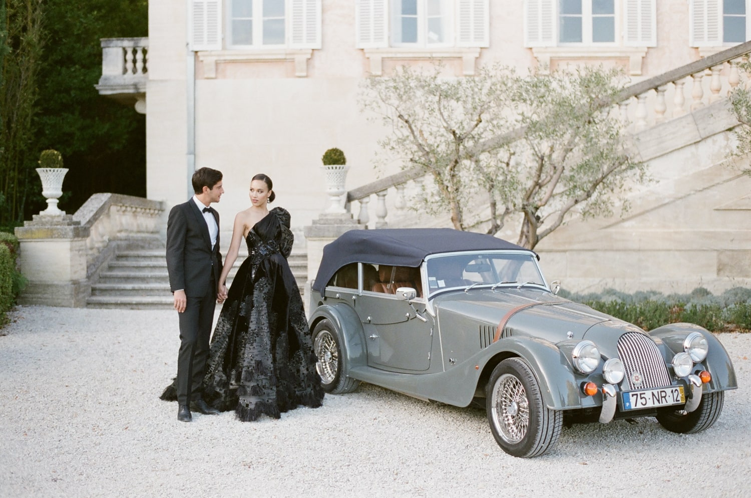Bride wearing a black wedding gown and holding her groom in front of a Rolls Royce in France