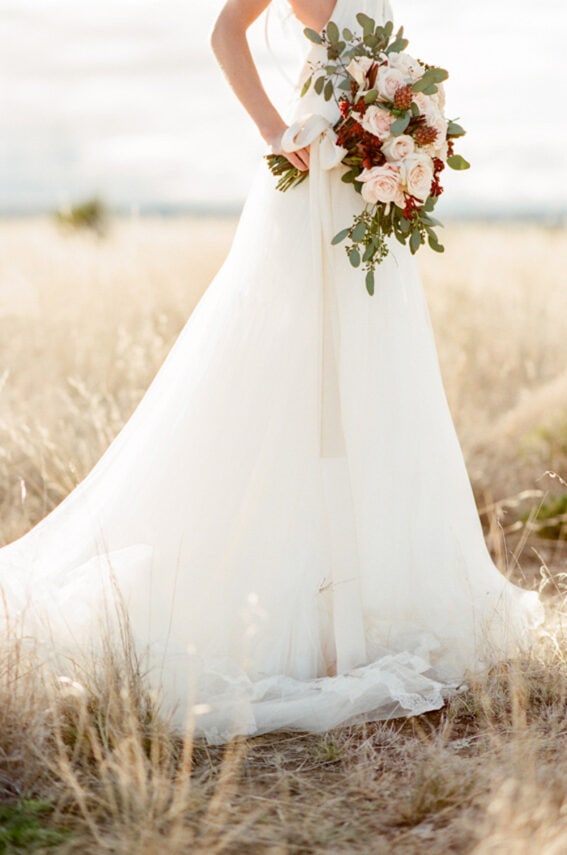 Closeup of a wedding bouquet and the skirt of a Vera Wang wedding gown