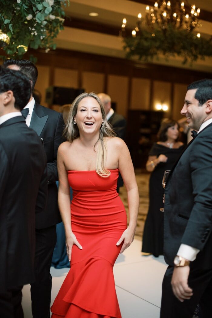Woman in red dress dancing during wedding reception and smiling into the camera