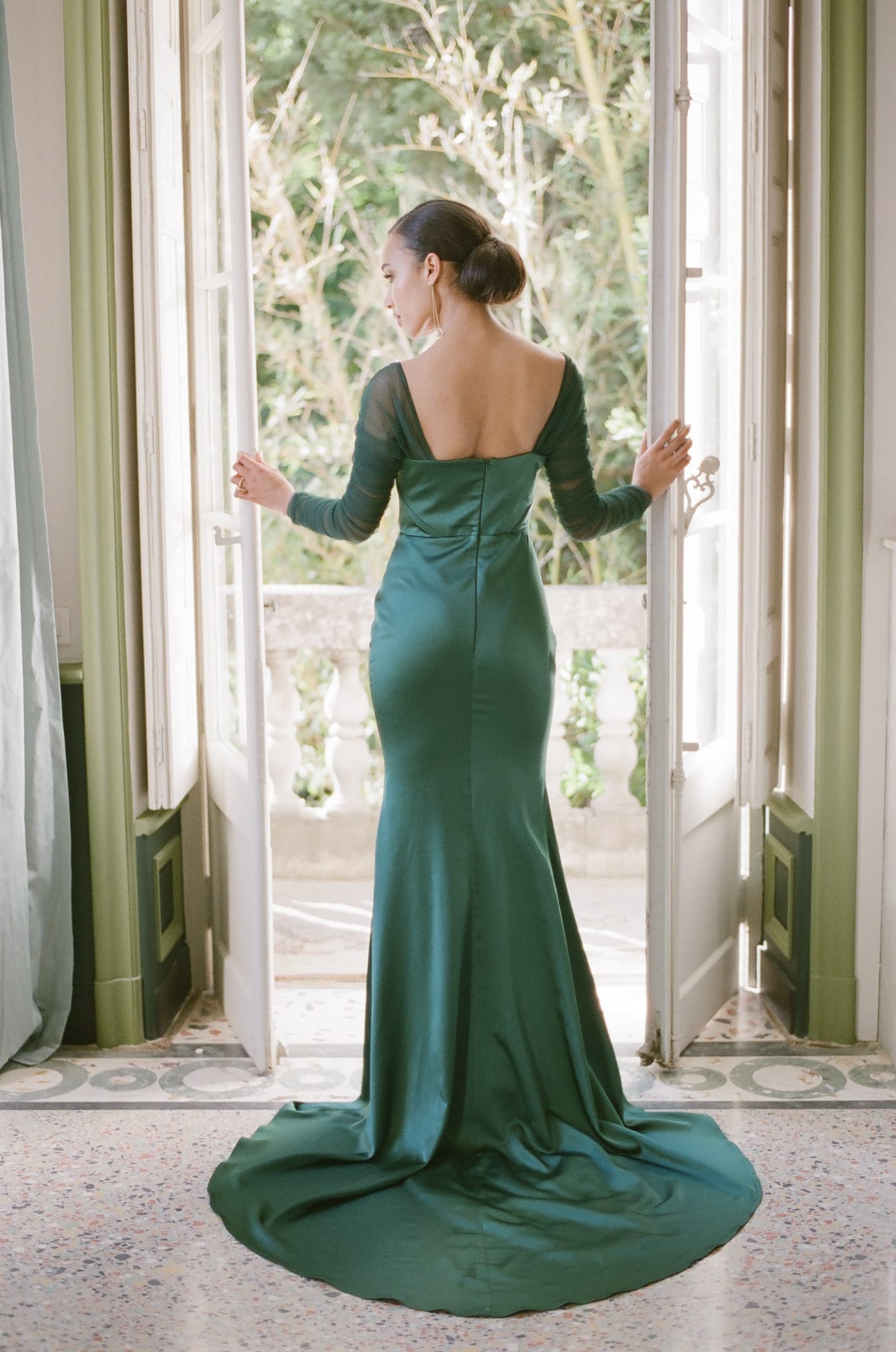 Bride standing in front of French windows holding them