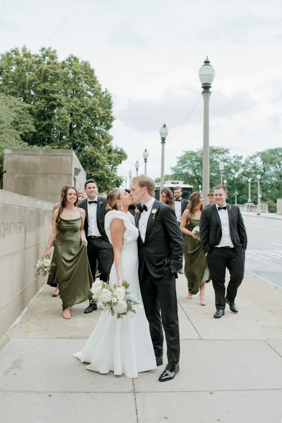 Bride and groom kissing each other in front of wedding party in Chicaog