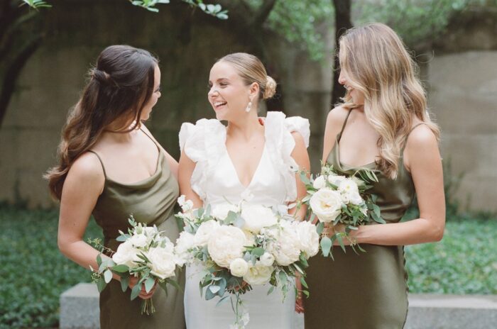 Bride smiling with her sisters while holding their bouquets