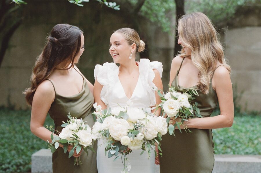 Bride smiling with her sisters while holding their bouquets