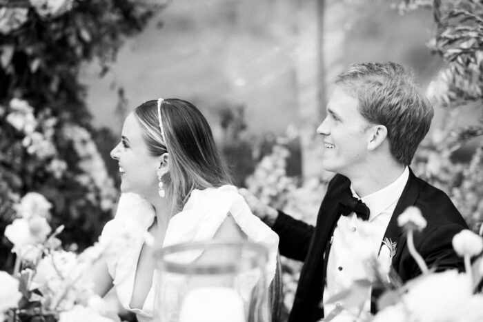 Black and white image of bride and groom smiling during wedding reception
