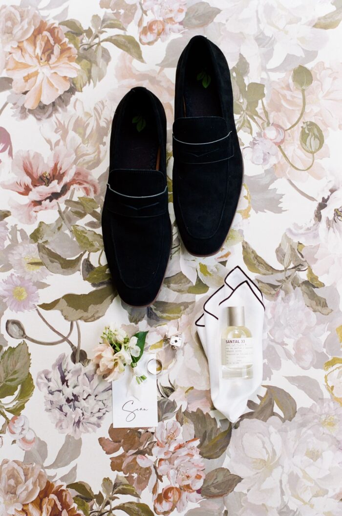 Black velvet men shoes displayed on floral backdrop