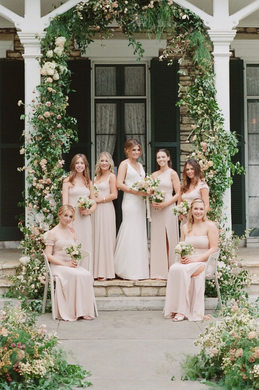 Bride and bridesmaids standing under ceremony arch at Oakland House