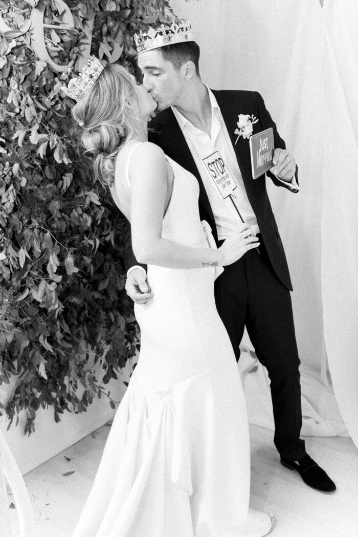 Bride and groom wearing crowns at photobooth