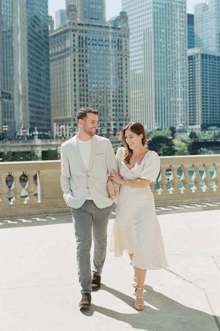 Bride and Groom walking arm in arm in front of the Wrigley Building in Chicago
