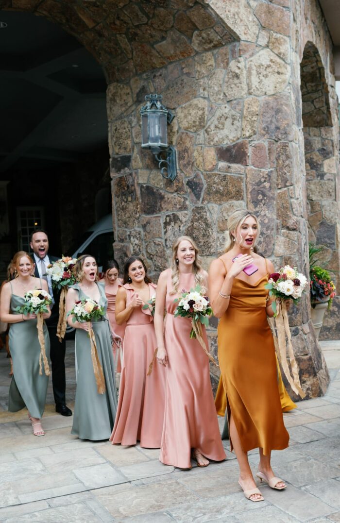 Bridesmaids in fall color dresses at first look with bride