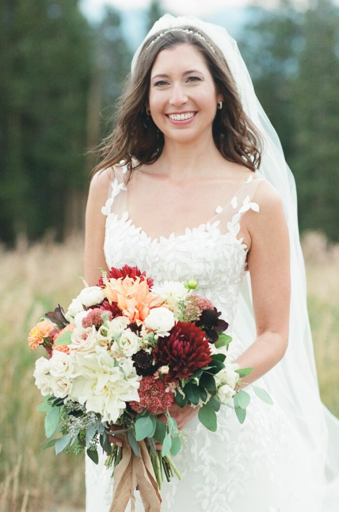 Bride in Mira Zwillinger wedding gown and her fall color bouqet