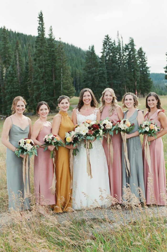 Bride with bridesmaids in orange, blush and blew bridesmaids dresses