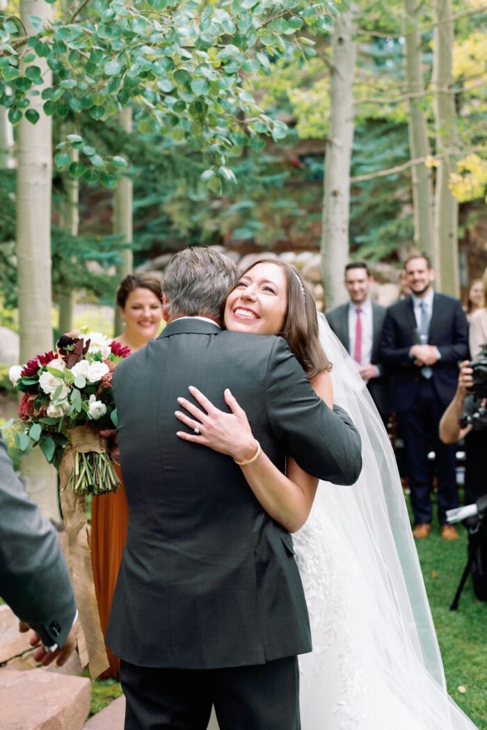 Bride and father of bride embracing each other during ceremony
