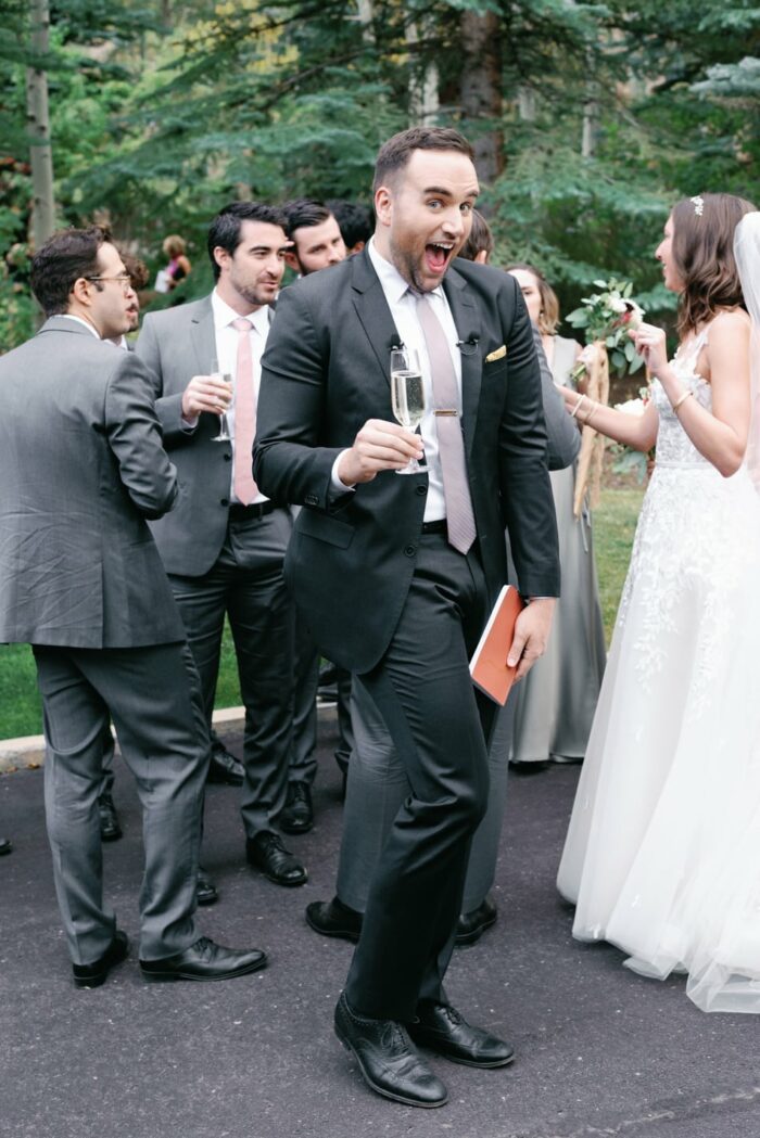 Officiant smiling into the camera with glass of champagne