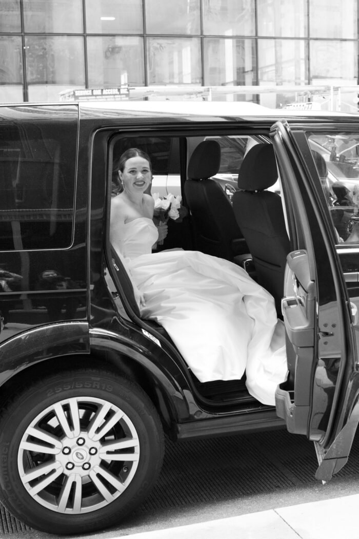 Bride in car driving up to St Vincent de Paul Chicago church