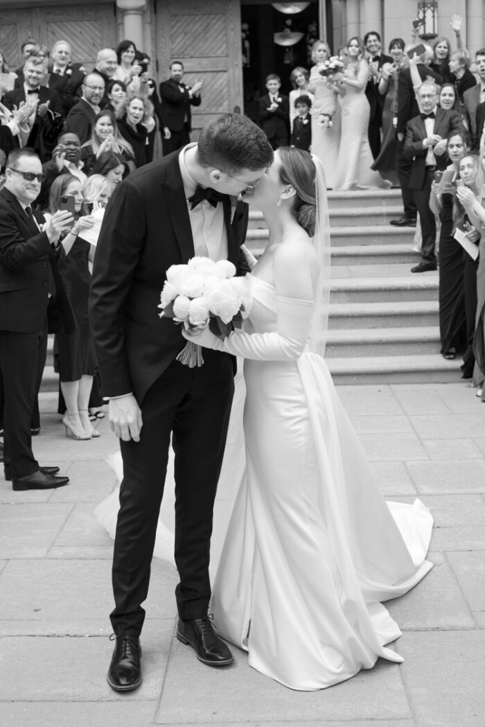 Bride and groom kissing each other in front of St Vincent de Paul church in Chicago