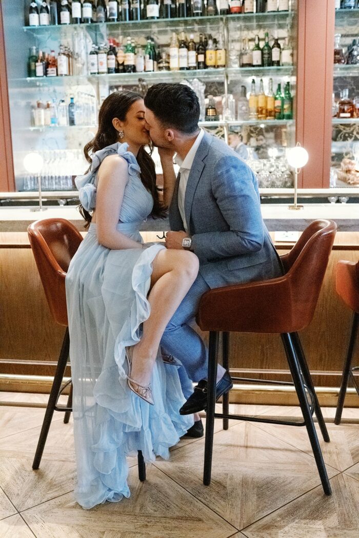 Bride and groom wearing blue and kissing at the bar at the Pendry Hotel in Chicago