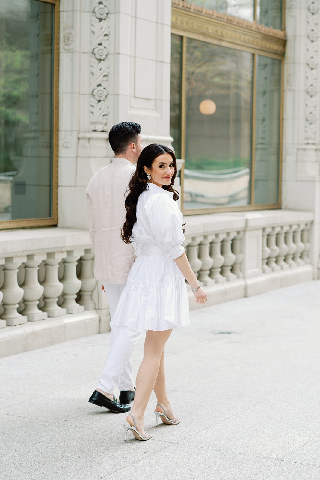 Bride and groom walking around Wrigley Building looking back